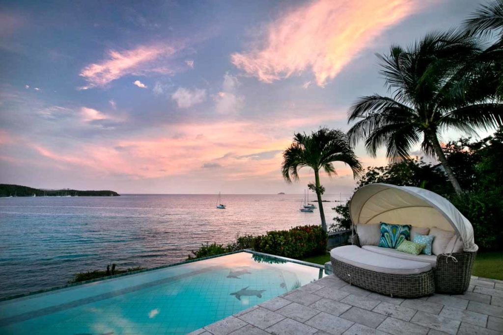 Poolside wicker lounge with fabric hood awning at sunset