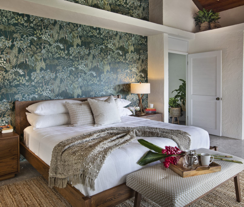 This master bedroom has a tropical wal paper accent wall that provides a pop of color to the fresh and cleanliness of the room.