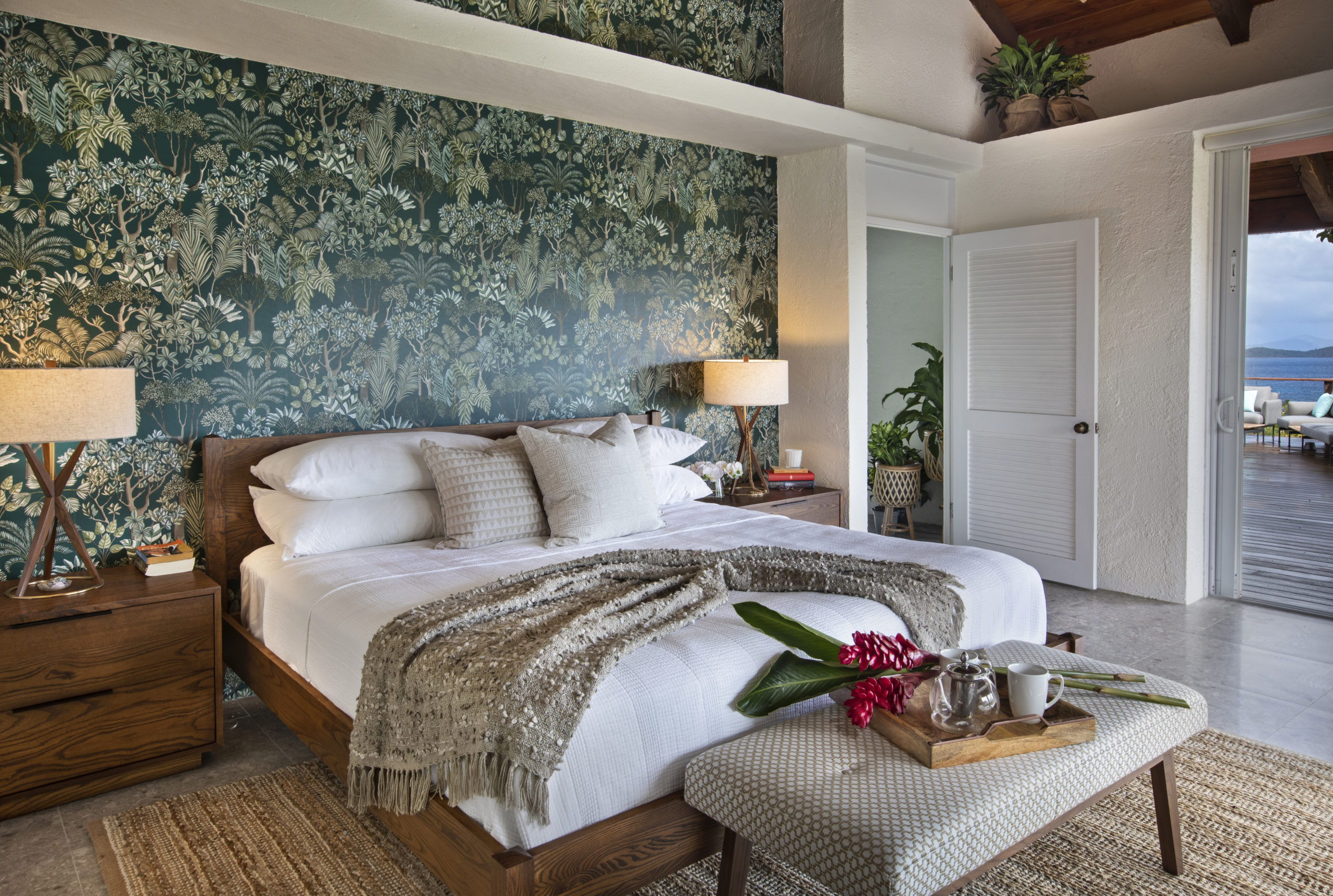 This master bedroom has a tropical wal paper accent wall that provides a pop of color to the fresh and cleanliness of the room.