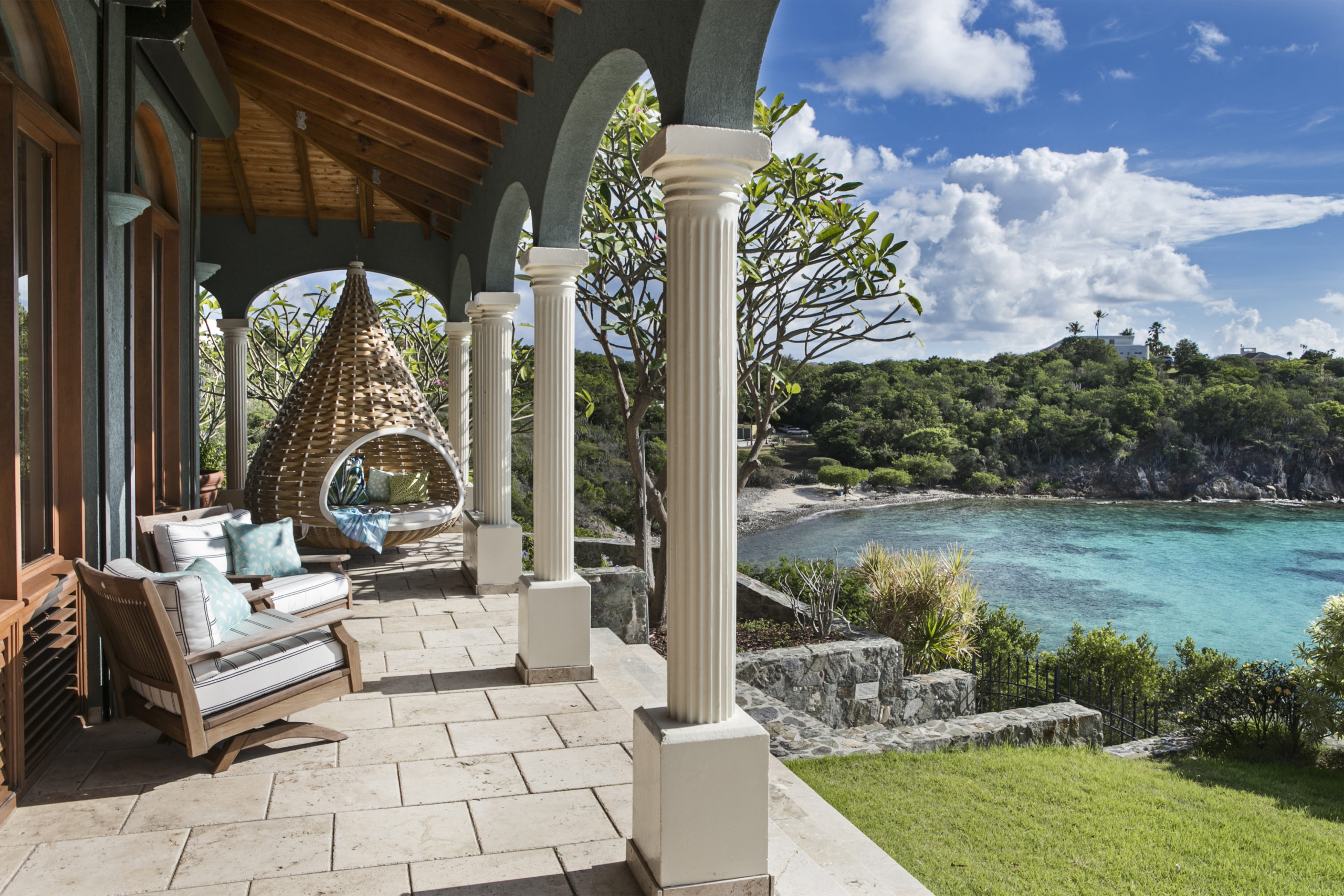 Beautiful porch in the caribbean complete with a hangning birdsnest daybed and views of the ocean.