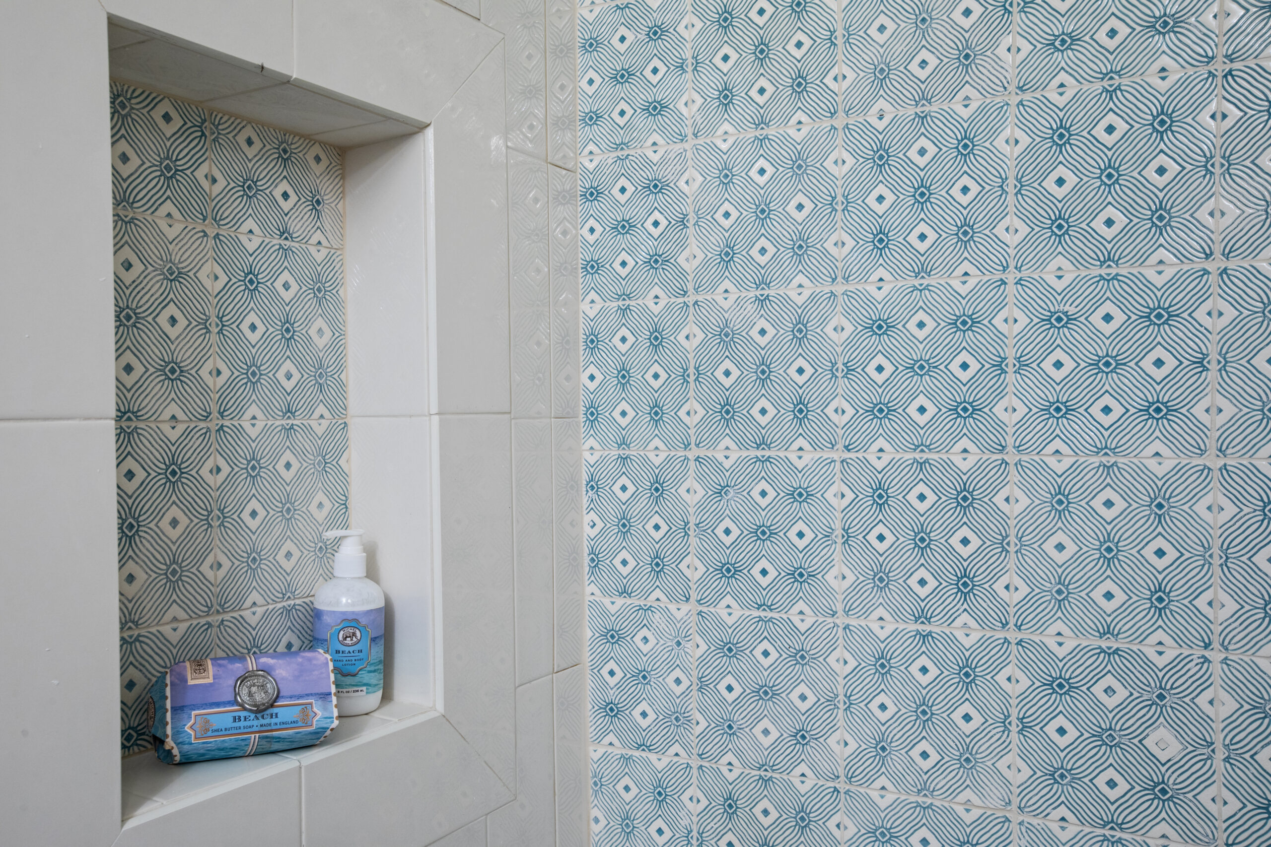 This shower has a custom turquoise tile detail and a custom shelf niche Lagnappe Custom Interiors