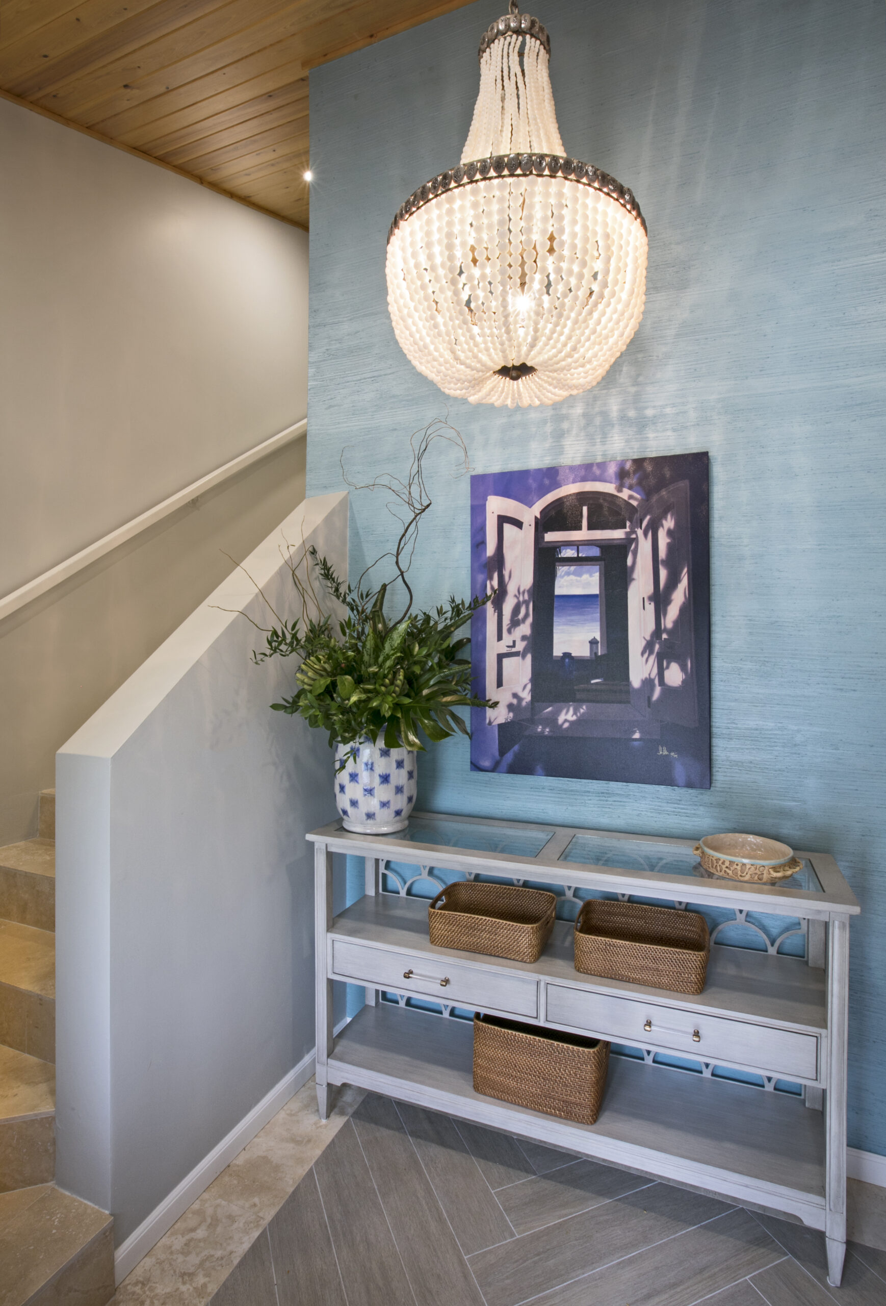 Whimsical island entry with a chandelier and wallcovering